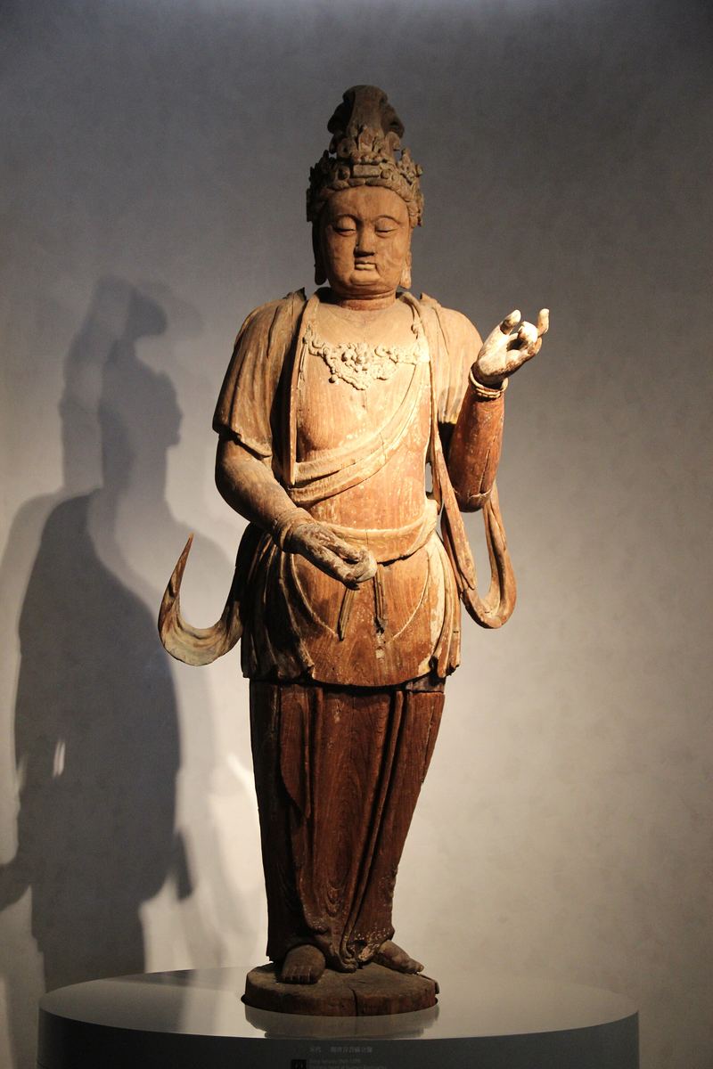 Holzfigur einer sitzenden Guanyin in entspannter Haltung
